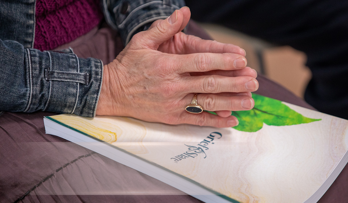A pair of hands are put on the Grief Share handbook.